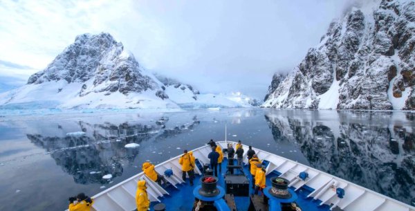 Cruising in Antarctica People in yellow jackets on the bow of a ship in Antarctica